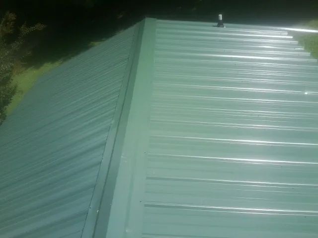 New green metal panels meeting at the ridge of a roof — Flat Roof Repair work by our crew in Hurlock