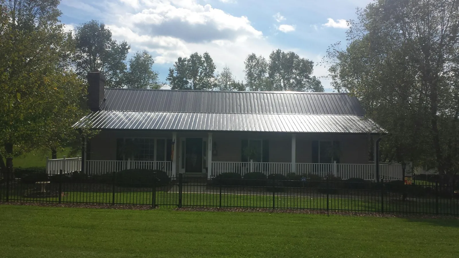 Gray metal roof on a brick ranch with a full width front porch — Gutter Guard Installation work by our crew in Hurlock