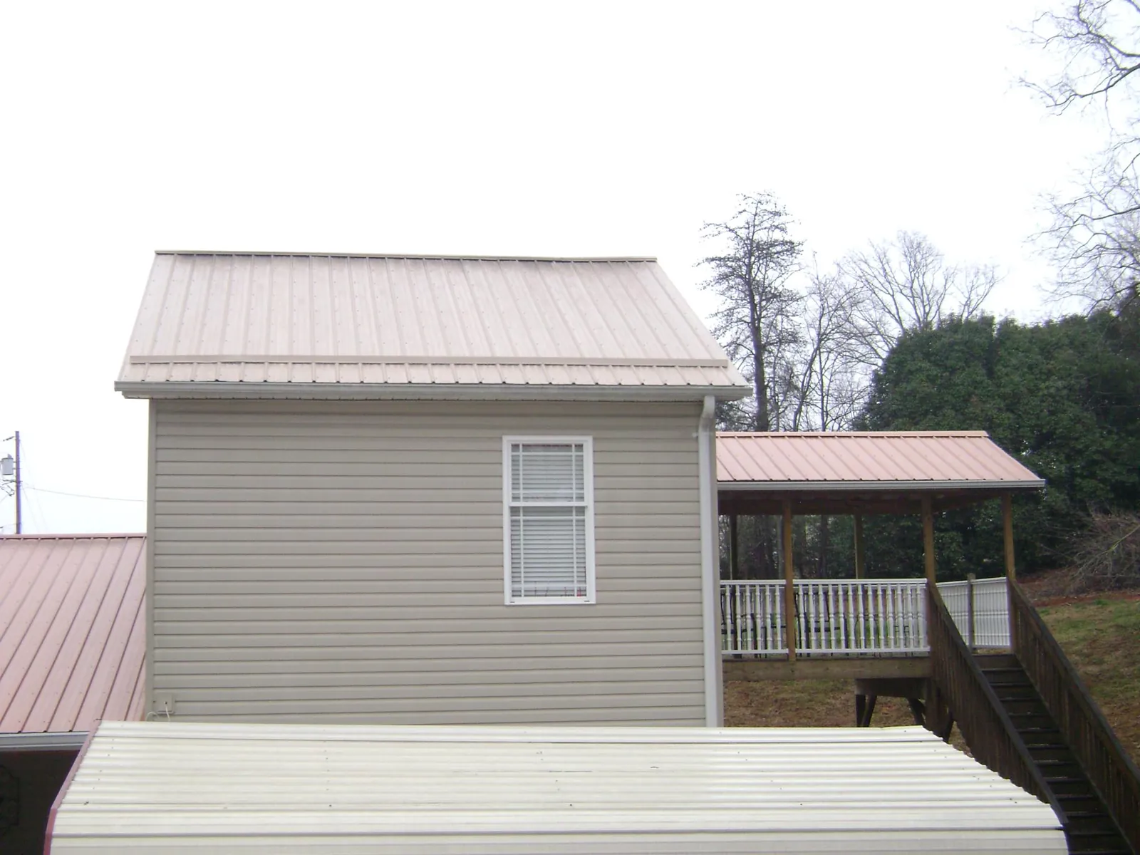 Tan metal roofs on a two story addition and attached porch, from a Roof Replacement job in Hurlock